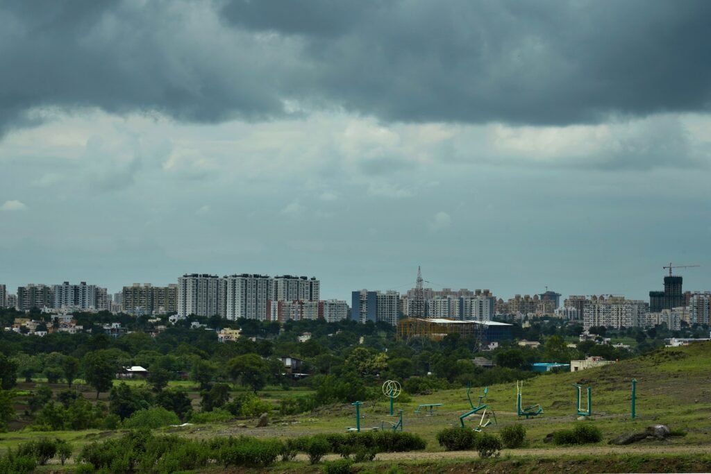 City skyline of Pune, Maharashtra with lush greenery and open gym equipment under dramatic cloudy skies.